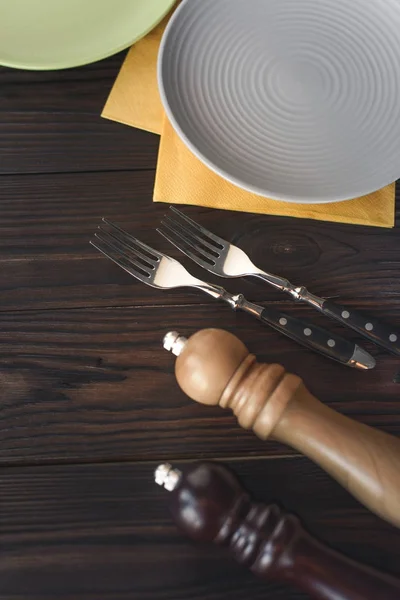 Flat lay with spices, steel forks and empty plates on wooden tabletop — Stock Photo