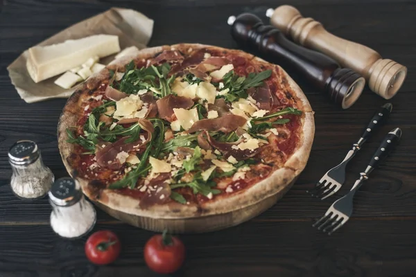 Vue rapprochée de pizzas italiennes, couverts et ingrédients sur bois — Photo de stock