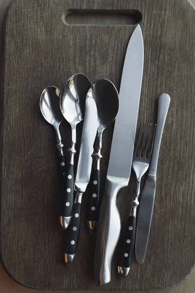 Top view of arrangement of steel dinnerware on wooden cutting board — Stock Photo
