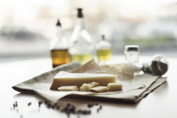 Selective focus of piece of cheese on napkin and oil in bottles — Stock Photo