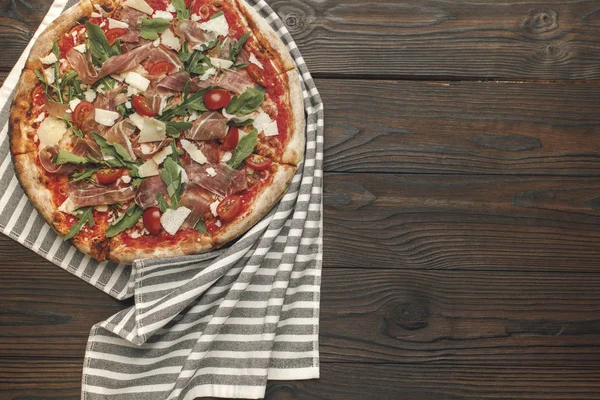 Vue de dessus de la pizza italienne et nappe sur la surface en bois — Photo de stock