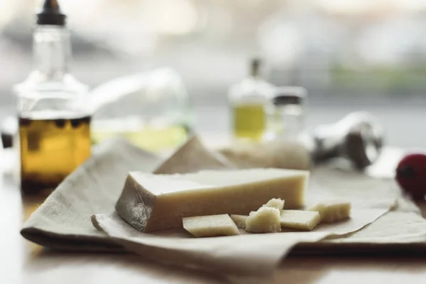 Foco selectivo de trozo de queso en la servilleta y aceite en botellas - foto de stock