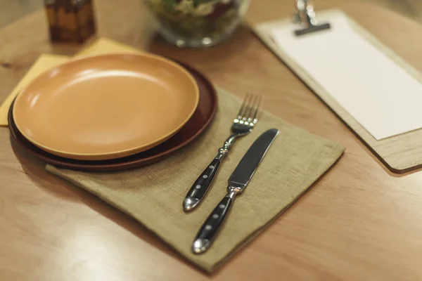 Selective focus of cutlery, empty plates and napkins on wooden tabletop — Stock Photo