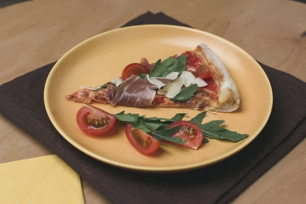 Vista de perto de pedaço de pizza italiana com tomate cereja no prato — Fotografia de Stock