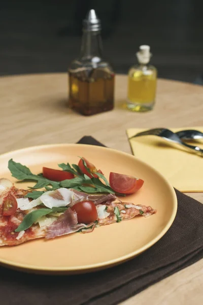 Vista de perto de pedaço de pizza italiana com tomate cereja no prato — Fotografia de Stock