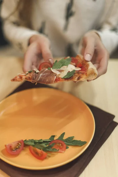 Vue partielle de la femme tenant un morceau de pizza italienne dans les mains — Photo de stock