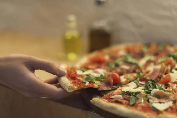 Plan recadré de femme prenant morceau de pizza italienne — Photo de stock