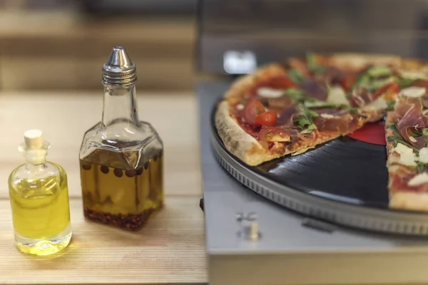 Vue rapprochée des types d'huile en bouteilles et pizza italienne sur tourne-disque vinyle — Photo de stock