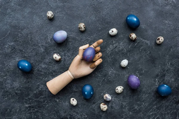 Mannequin hand with painted chicken and quail eggs on dark background — Stock Photo
