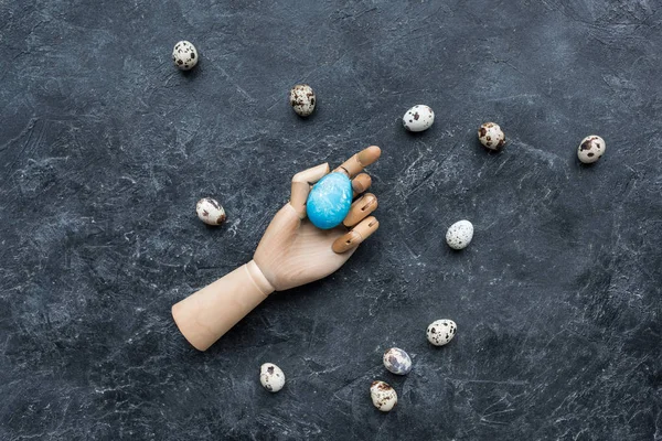 Uova di quaglia intorno manichino mano con uovo colorato su sfondo scuro — Foto stock