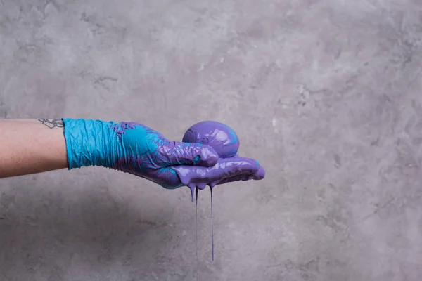 Woman holding egg in paint on grey background — Stock Photo