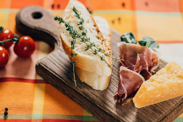 Крупным планом нарезанный багет, мясо и сыр пармезан на деревянной доске — стоковое фото