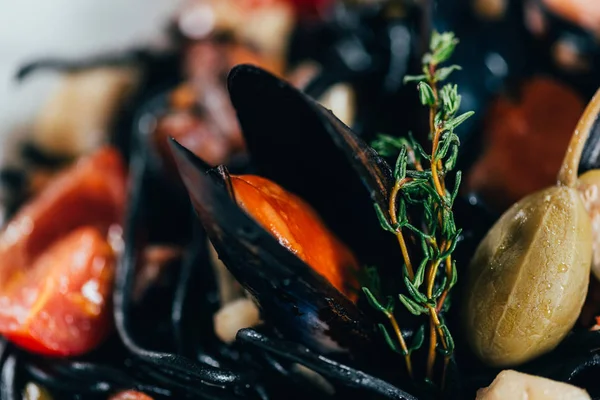 Крупный план вкусных спагетти с чернилами каракатицы, кальмаров и мидий с осьминогом — стоковое фото