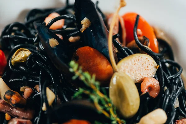 Close-up view of gourmet spaghetti with cuttlefish ink, squid and mussels with octopus — Stock Photo