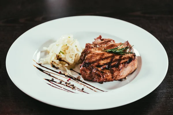 Delicious grilled juicy steak with rosemary and sauce on plate — Stock Photo