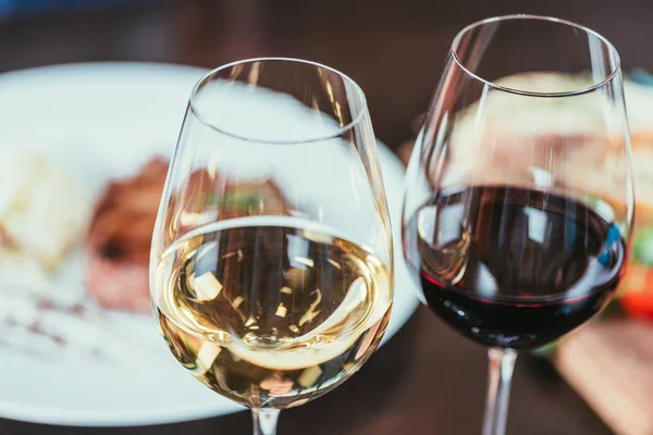 Vista de cerca de dos copas con vino tinto y blanco en la mesa en el restaurante - foto de stock