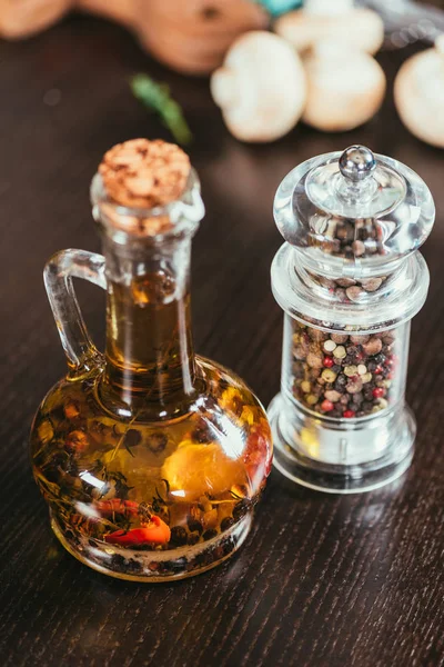 Aceite de oliva con especias en botella de vidrio y condimentos en recipiente - foto de stock