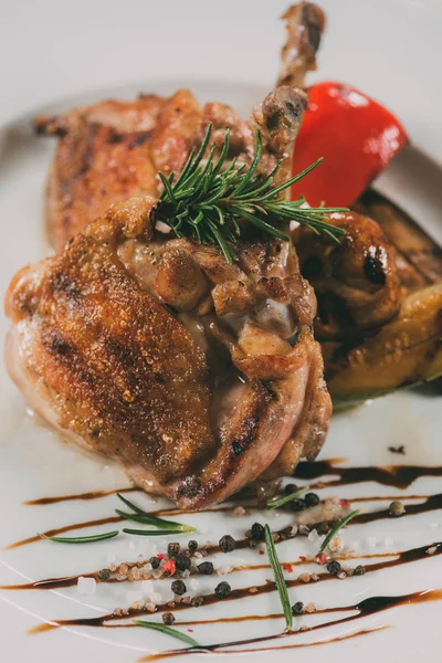 Close-up view of gourmet roasted chicken with rosemary, spices and sauce on plate — Stock Photo