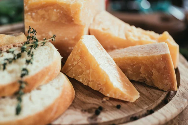 Крупним планом смачний пармезанський сир і скибочки свіжого багета на дерев'яній обробній дошці — стокове фото