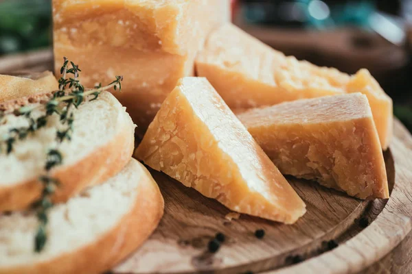 Vista de cerca del delicioso queso parmesano y rebanadas de baguette fresca en la tabla de cortar de madera - foto de stock