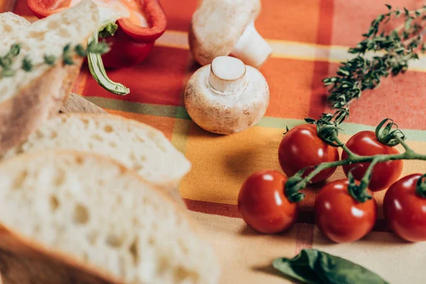 Fresh ripe cherry tomatoes, mushrooms and sliced bread on table napkin — Stock Photo