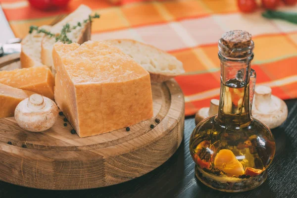 Fromage baguette et parmesan sur planche à découper en bois et huile avec épices dans une cruche en verre sur table — Photo de stock