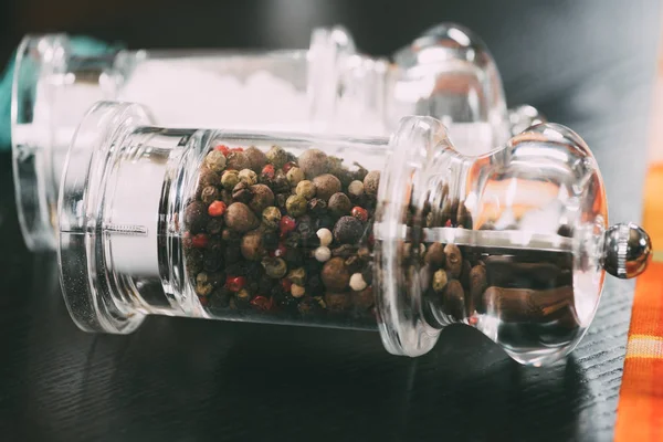 Concentration sélective du sel et des grains de poivre dans des récipients en verre — Photo de stock