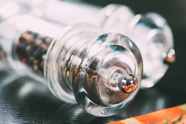 Vue rapprochée du sel et des grains de poivre dans des récipients en verre sur la table — Photo de stock