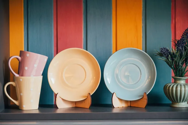 Close-up view of decorative empty plates and cups near colorful wall in restaurant — Stock Photo