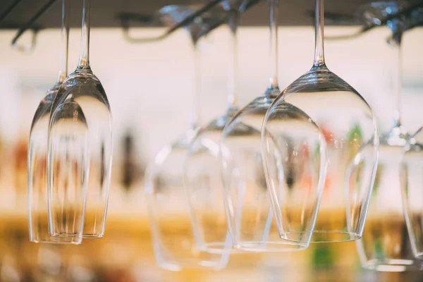 Mise au point sélective de verres à vin vides propres suspendus dans le comptoir du bar — Photo de stock