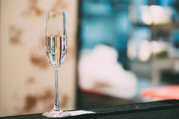 Vista de cerca de una sola copa de vino con líquido transparente en el mostrador de la barra - foto de stock