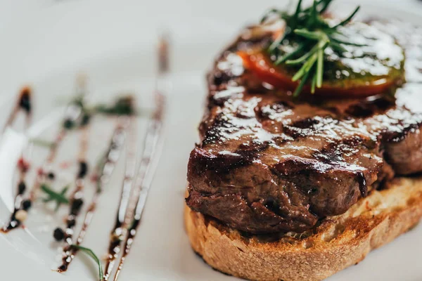 Foco seletivo de delicioso bife suculento com alecrim e pão assado no prato — Fotografia de Stock