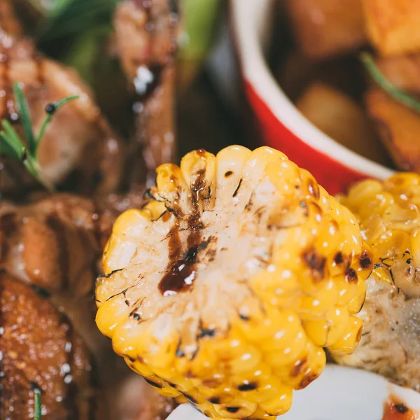 Close-up view of tasty grilled corn and roasted chicken with sauce and rosemary — Stock Photo