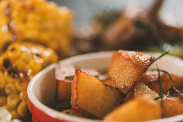 Enfoque selectivo de sabroso maíz a la parrilla con patatas asadas en el plato - foto de stock