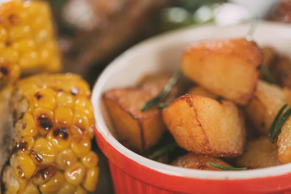 Vue rapprochée de savoureux maïs grillé avec pommes de terre rôties sur assiette — Photo de stock