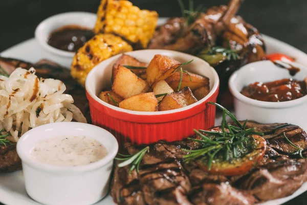 Vista de perto de legumes grelhados, asas de frango assadas e bifes de carne com batatas no prato — Fotografia de Stock