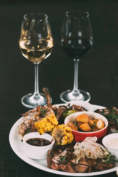 Glasses of wine and plate with gourmet grilled vegetables and meat on table in restaurant — Stock Photo