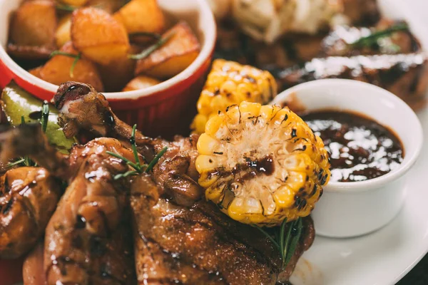 Vista de cerca de deliciosas alitas de pollo a la parrilla con maíz y salsa - foto de stock