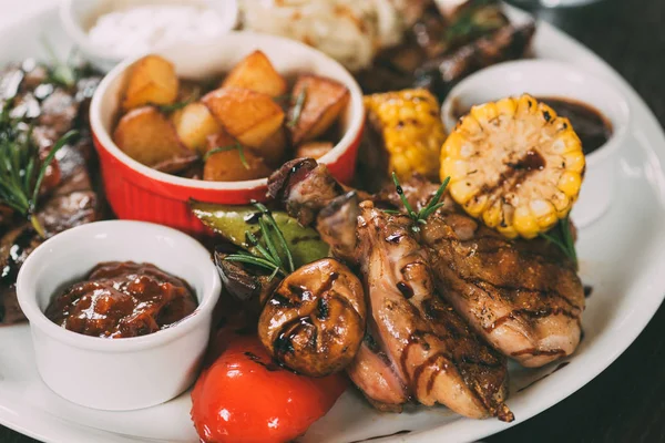 Gustoso pollo alla griglia con patate fritte, mais, funghi e salsa sul piatto — Foto stock