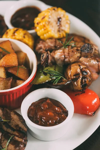 Leckeres Grillhähnchen mit Bratkartoffeln, Mais und Sauce auf dem Teller — Stockfoto