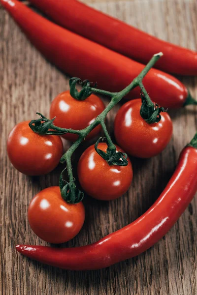 Vista de perto de tomates cereja maduros frescos e pimentas na mesa de madeira — Fotografia de Stock