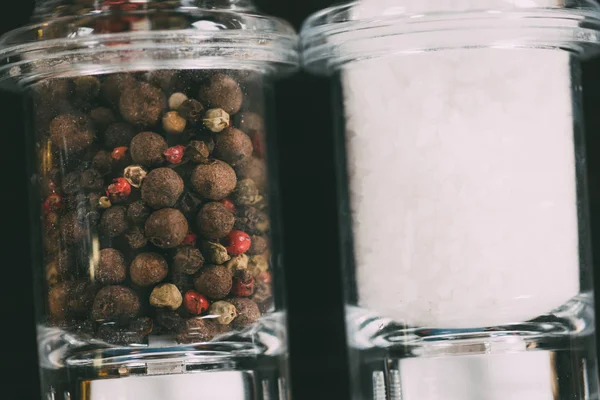 Close-up view of salt and peppercorns in glass containers — Stock Photo