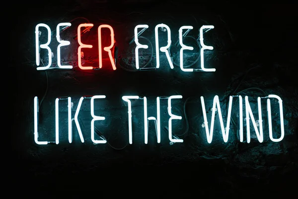 Bier frei wie die Wind-Neon-Inschrift an der dunklen Wand in der Bar — Stockfoto