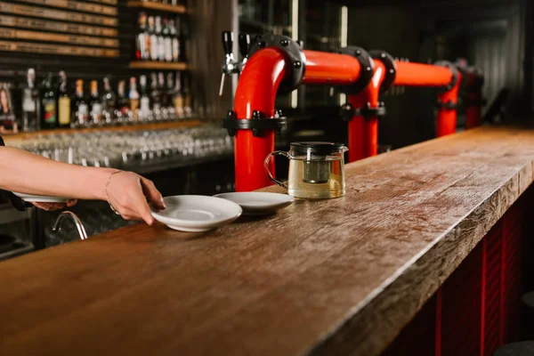 Cropped shot of person putting empty plates on wooden bar counter — Stock Photo