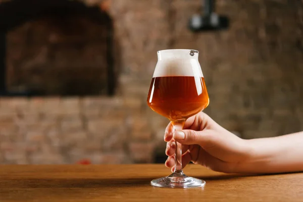 Partial view of person holding glass of fresh cold beer in pub — Stock Photo