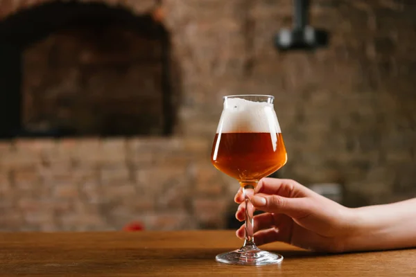 Tiro recortado de la persona sosteniendo vaso de cerveza fría fresca en el bar - foto de stock