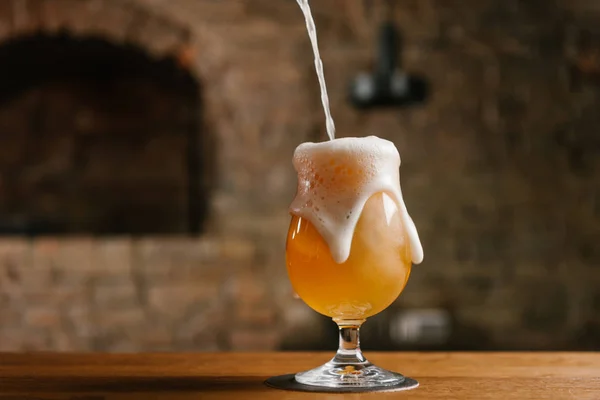 Vue rapprochée de verser de la bière fraîche froide avec de la mousse dans du verre dans un bar — Photo de stock