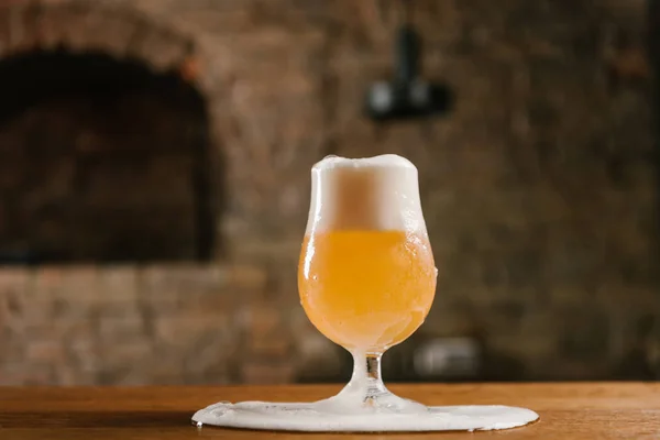 Close-up view of delicious fresh beer and foam spilled on table in pub — Stock Photo