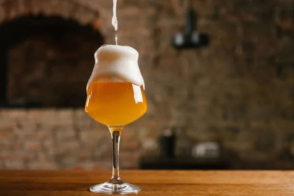 Vista de cerca de verter cerveza con espuma en el vidrio en el pub - foto de stock