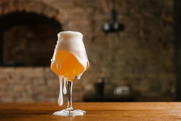 Vista close-up de cerveja gelada com espuma em vidro na mesa de madeira — Fotografia de Stock